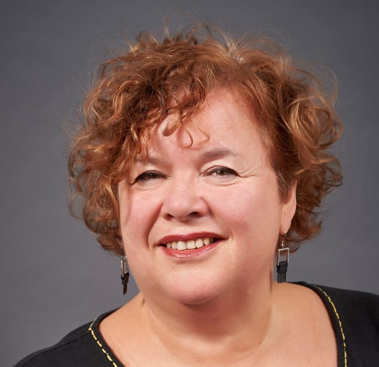 A woman with short, curly red hair.