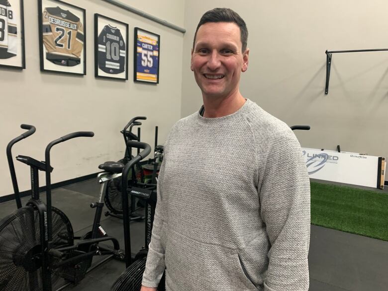 Man stands in front of gym equipment.