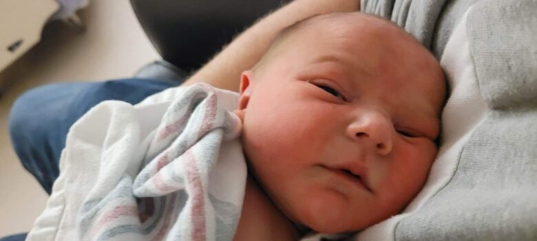 A newborn baby squints at a camera.