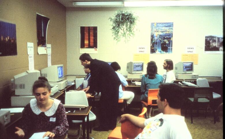 Students and teachers gather around old computers in a classroom in 1993.