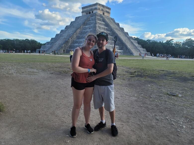 A man and woman stand in front of the Temple of Kukulcan in Mexico.