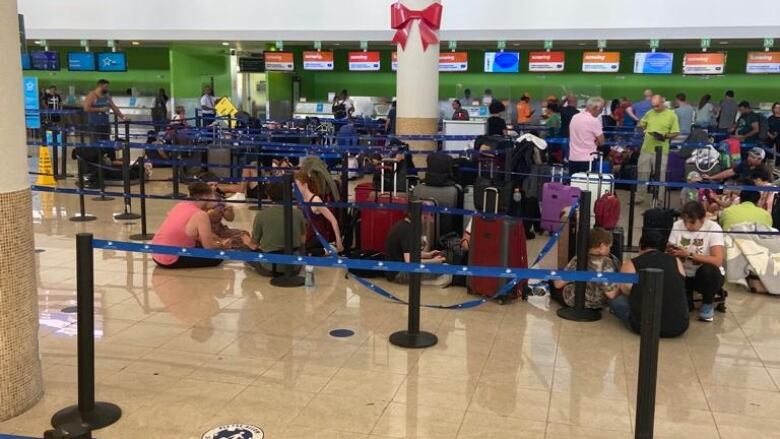 People are sitting on airport floor.