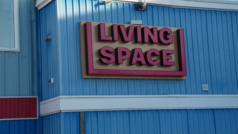 The front of a blue building with a red sign that says 'Living Space.'