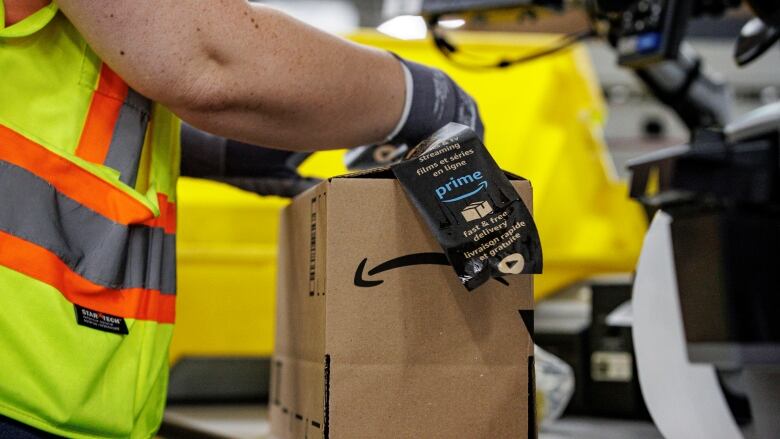 A worker adds a label to a shipment box in a warehouse.