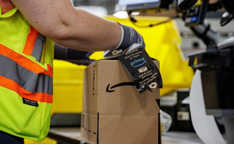 A worker adds a label to a shipment box in a warehouse.