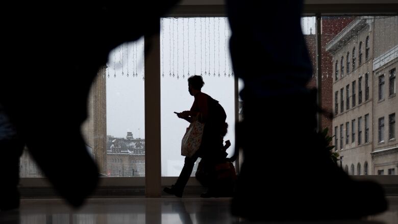 Silhouettes of people near a shopping mall window.