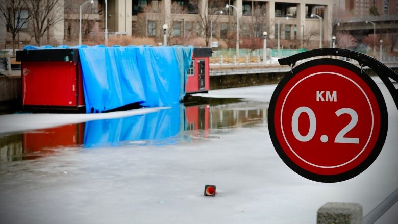 A distance marker next to a partially frozen waterway.