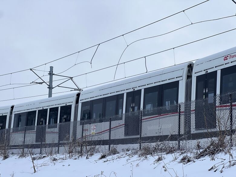 An overhead wire droops down toward a light rail train.