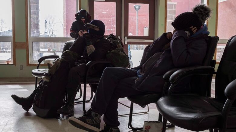 A group of people sit on a bench together. 