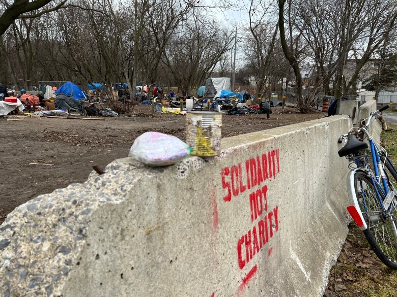 Tents and tarps can been seen being a cement barrier with the words 