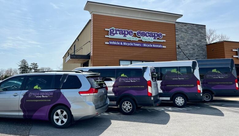 Four tour vans are parked outside the Grape Escape office. 