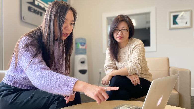 Realtor Wei Chein (left), and her client Dany Yang look at P.E.I. real estate listings.  With new federal rules now in effect, Yang is no longer able to buy a home in the Charlottetown area. 