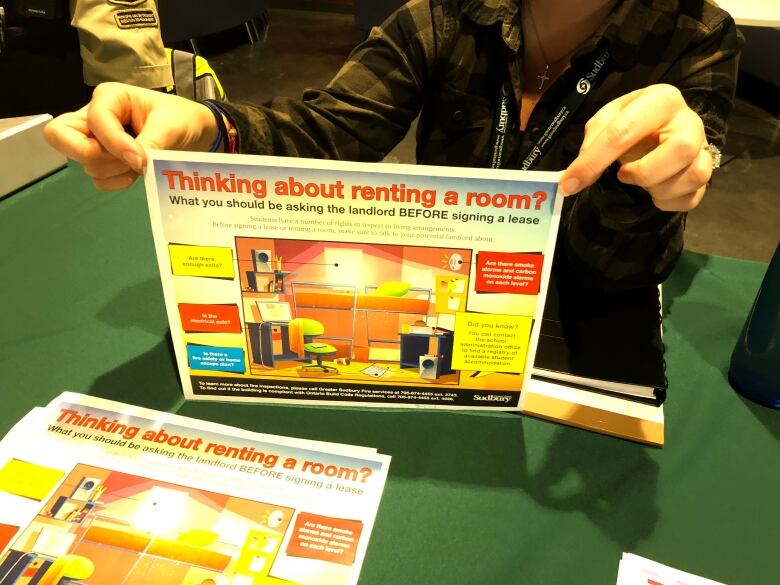 A woman holds a leaflet about what students should know if renting a room off-campus.