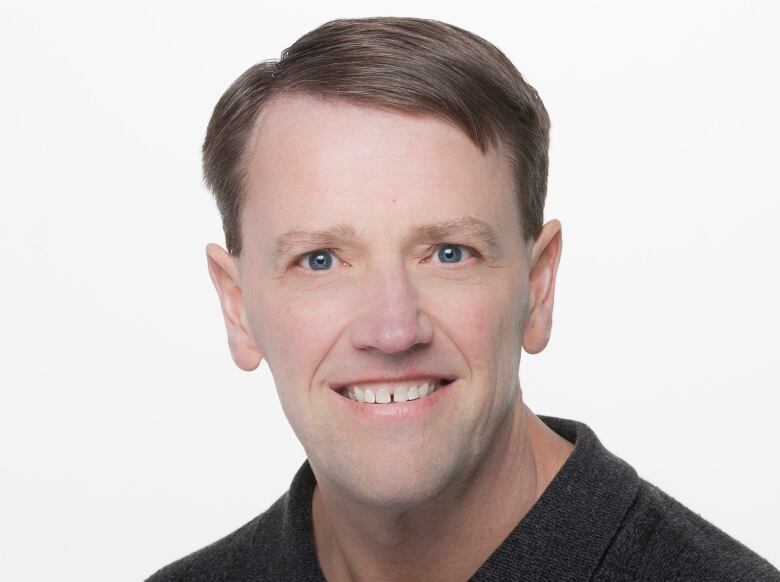 A headshot of a man in front of a white background