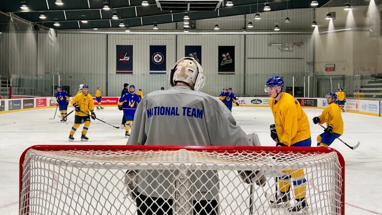 Several hockey players are seen practicing at a ice rink.