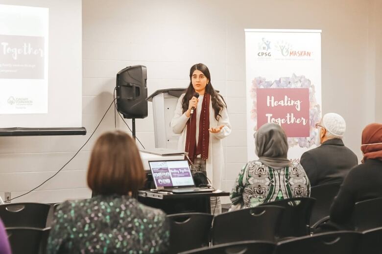 A woman speaks to a group of people in a small room