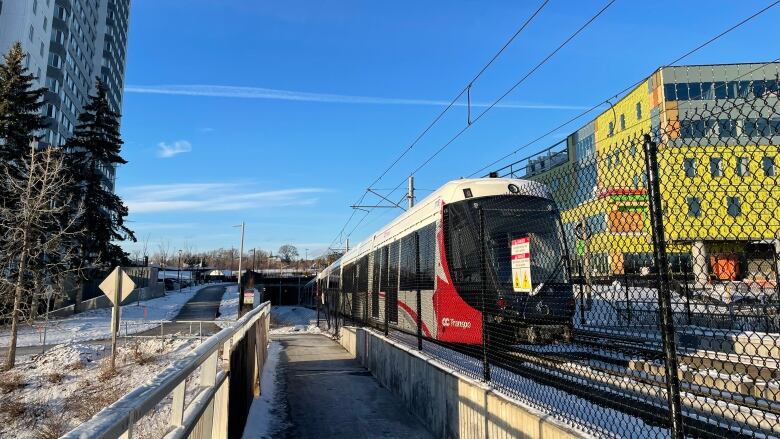 A red-and-white train sits on train tracks on a sunny winter afternoon.