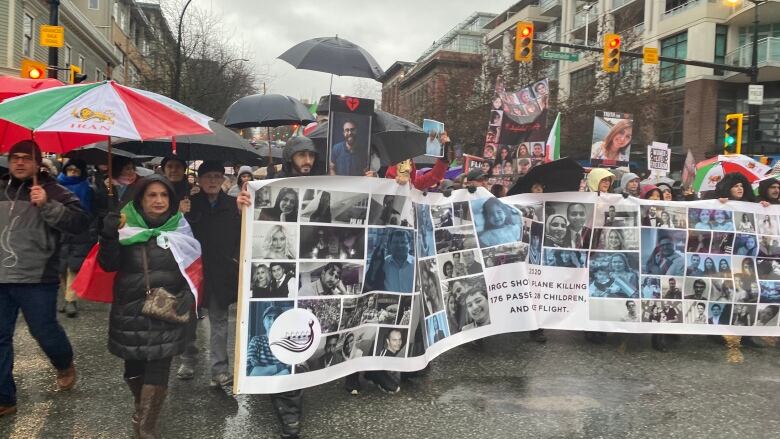 A crowd of people holding a banner march on the streets on North Vancouver.