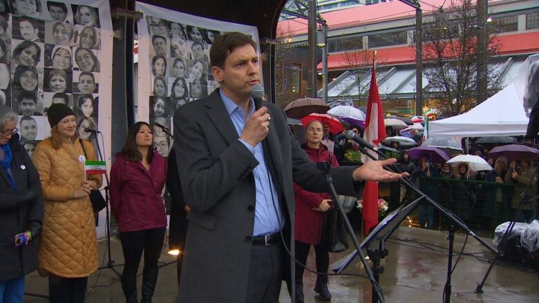 B.C. Premier David Eby holds a microphone and speaks to a crowd in North Vancouver.