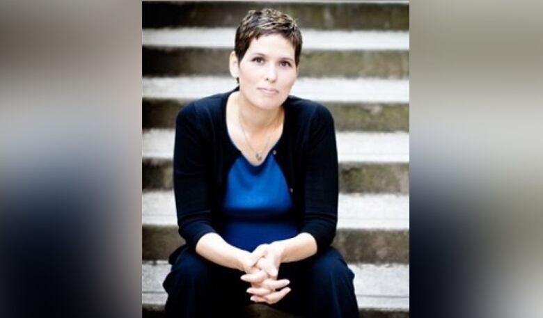 A woman sits looking at the camera for a professional portrait.