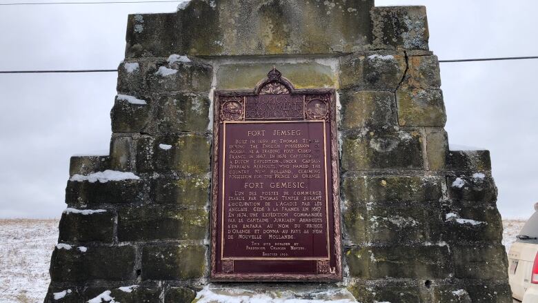 close up of stone monument with plaque on snowy day