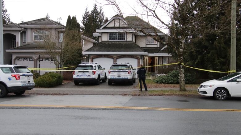 A house in Surrey is blocked off with police tape after three bodies were found inside.