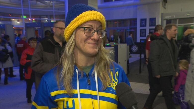 A woman in Ukraine's colours of blue and yellow stands inside the entrance of Canada Life Centre in Winnipeg.