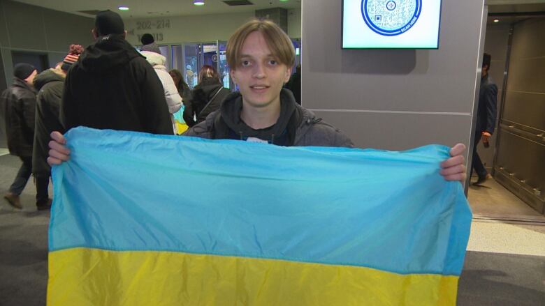 A teen holds out a blue and yellow flag.