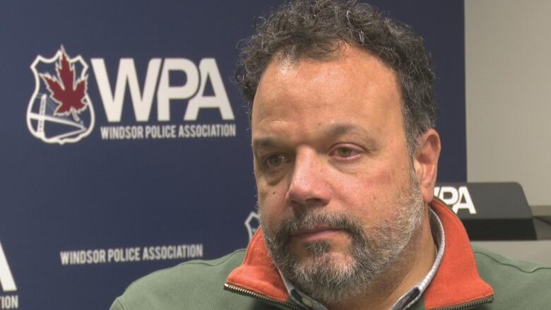 Shawn McCurdy sits in front of a blue banner that says WPA Windsor Police Association