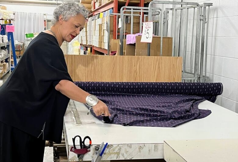 Profile view of a woman rolling out fabric on a table