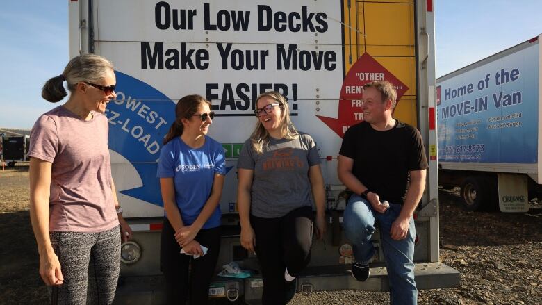 Four people stand in front of a U-Haul truck.