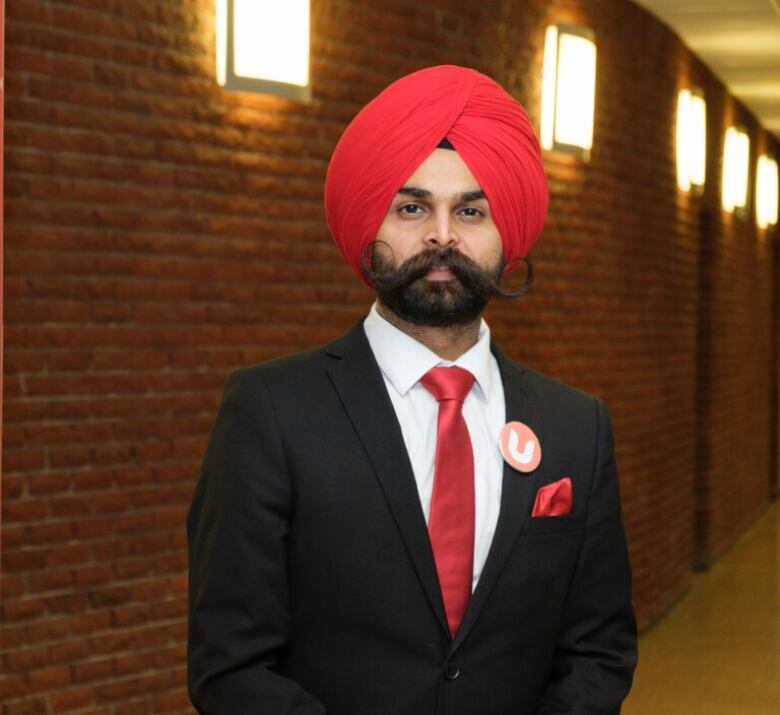 A man poses for a picture against a brick wall. 