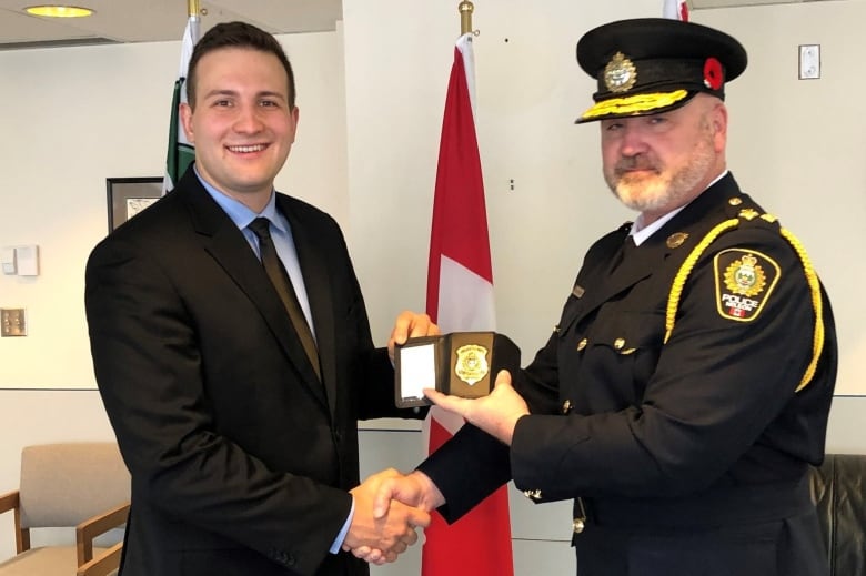 A police constable is pictured smiling as he accepts his badge from the chief of the Nelson Police Department.