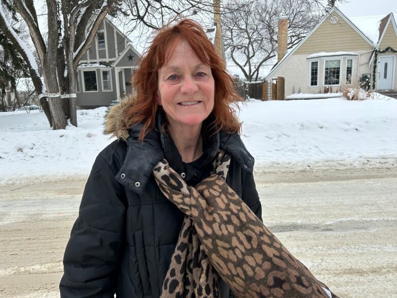 A woman is standing in a street with houses in the background.