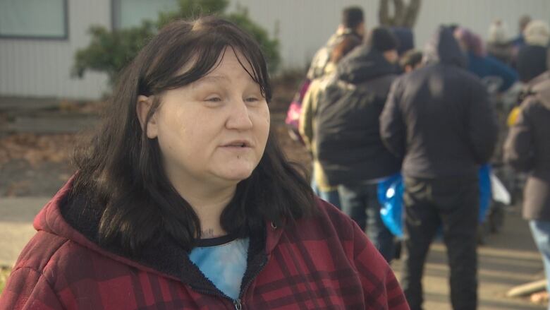 Olivia Fletcher is standing in a plaid jacket outside the Fraser Valley food bank explaining her hope that more people will donate to the food bank.