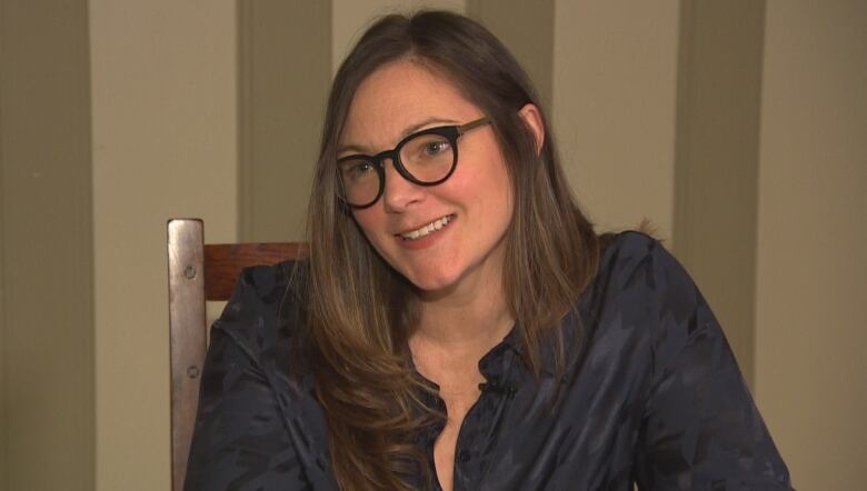 A woman sitting in a chair, smiles.