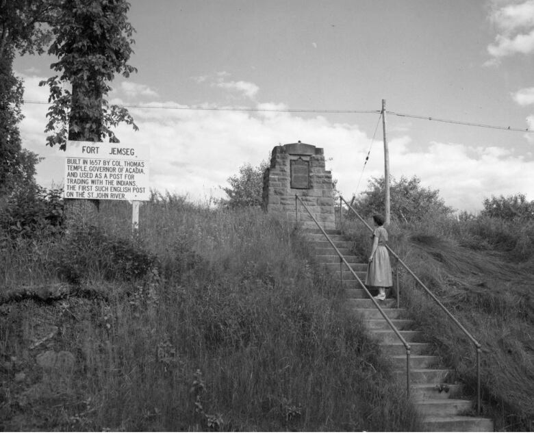 black and white photo of woman on steps leading up to stone monument