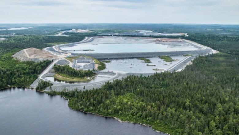 This aerial photo shows a large poind near a gold mine. A lake can be seen in the foreground.