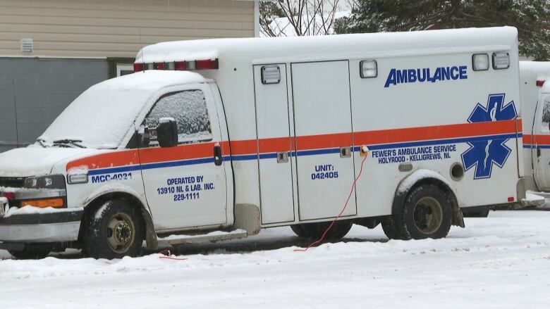 A snow covered ambulance sits in a parking lot.