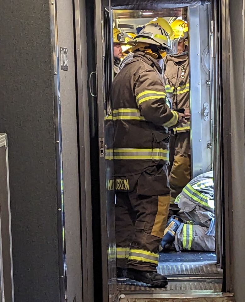 Firefighters aboard gather between cars on a disabled train.