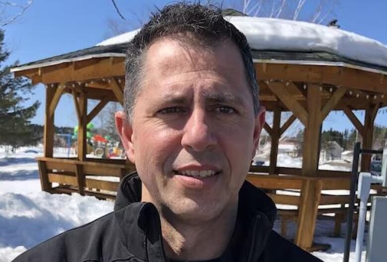 A man in front of a snowy gazebo