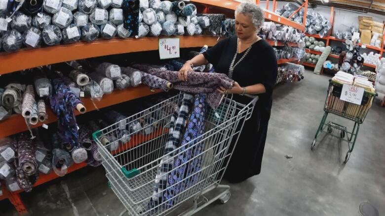 A woman with a shopping cart examines fabric