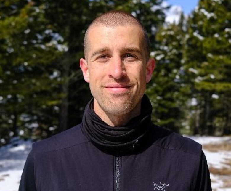 A man poses for a profile picture. He's standing outside in snowy conditions. 