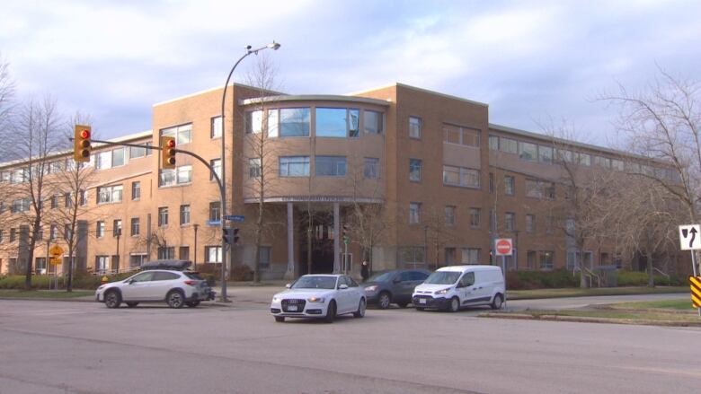 A beige building is pictured on a street corner.