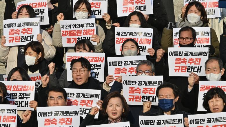 Several people are shown chanting while holding up signs.