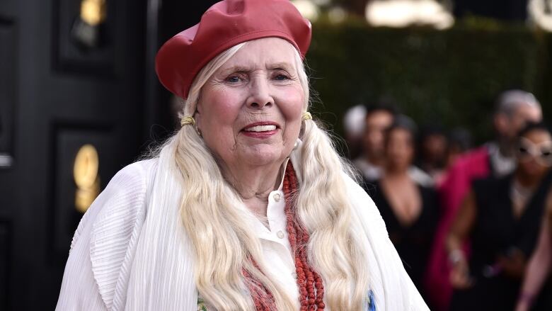 A smiling woman wears blonde pigtails and a red beret.