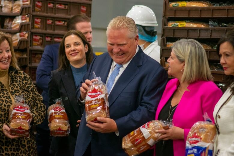 People standing and holding bags of bread.