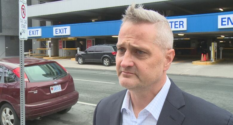 A man stands in front of a parking lot.