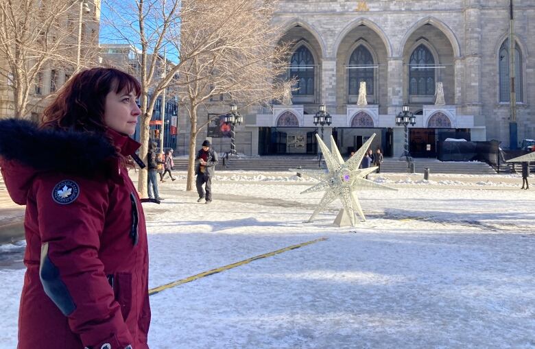 A woman wearing a burgundy jacket stands in front of the Notre-Dame Cathedral in Old Montreal.