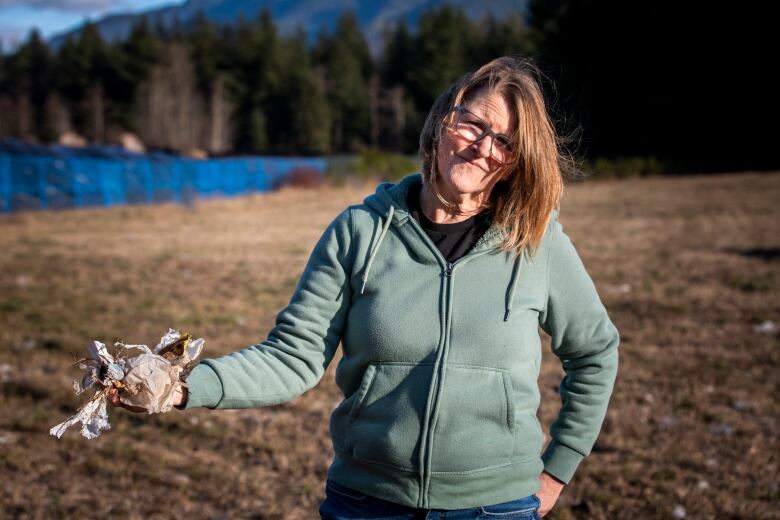 D'Arcy Henderson holds a handful of trash that blew from business waste piles into a neighbouring property.